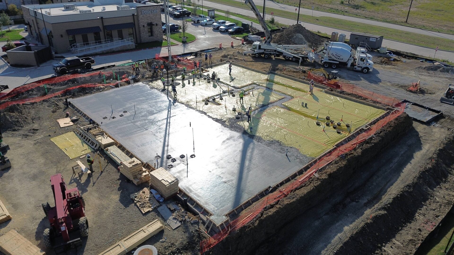 Aerial view of a construction site with workers pouring concrete.